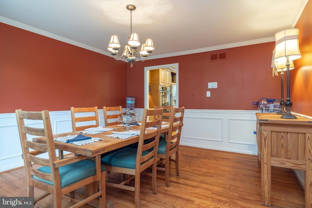 17 Bridleshire Rd, Newark, DE 19711 - dining space with a chandelier, crown molding, wainscoting, wood finished floors, and a decorative wall