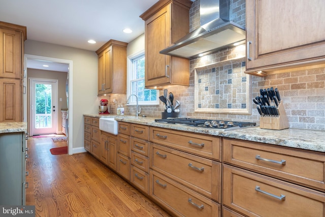 17 Bridleshire Rd, Newark, DE 19711 - kitchen with wall chimney range hood, brown cabinets, a sink, light stone countertops, and wood finished floors
