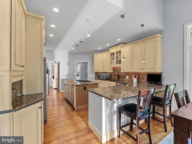 928 Township Line Rd, Chalfont, PA 18914 - kitchen featuring cream cabinetry, light wood finished floors, a center island, tasteful backsplash, and stainless steel gas cooktop