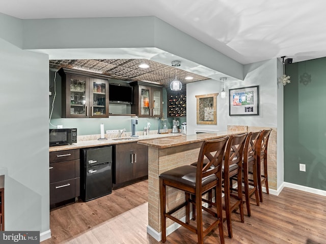 928 Township Line Rd, Chalfont, PA 18914 - indoor wet bar with black microwave, fridge, and light wood-type flooring