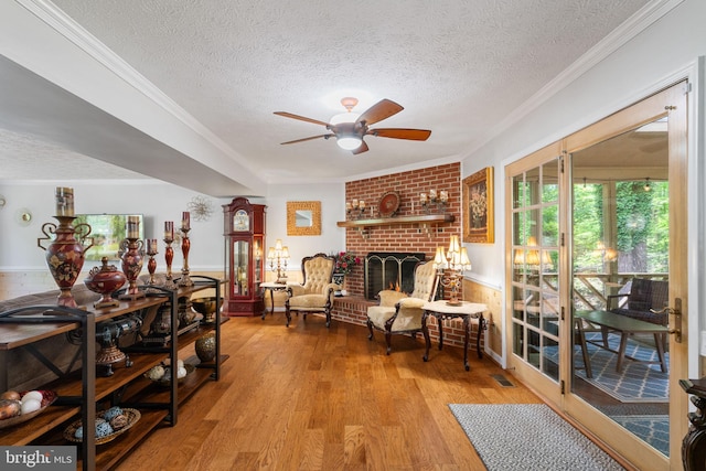 175 Mt Hope Church Rd, Stafford, VA 22554 - living area featuring a textured ceiling, ceiling fan, light wood-type flooring, a fireplace, and crown molding