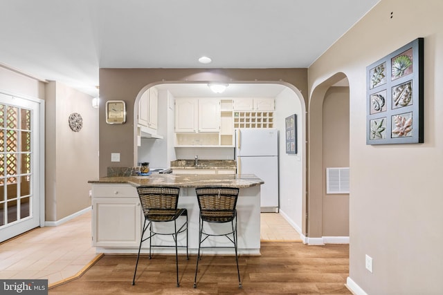 175 Mt Hope Church Rd, Stafford, VA 22554 - kitchen featuring freestanding refrigerator, arched walkways, a peninsula, and white cabinets