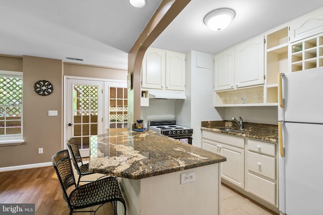 175 Mt Hope Church Rd, Stafford, VA 22554 - kitchen with freestanding refrigerator, electric range, under cabinet range hood, a kitchen bar, and a peninsula