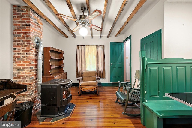 13220 Bank St, Bishopville, MD 21813 - living area featuring a wood stove, hardwood / wood-style floors, ceiling fan, and beam ceiling
