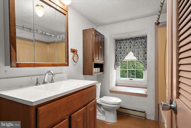 13220 Bank St, Bishopville, MD 21813 - bathroom featuring baseboard heating, a textured ceiling, vanity, toilet, and wood finished floors