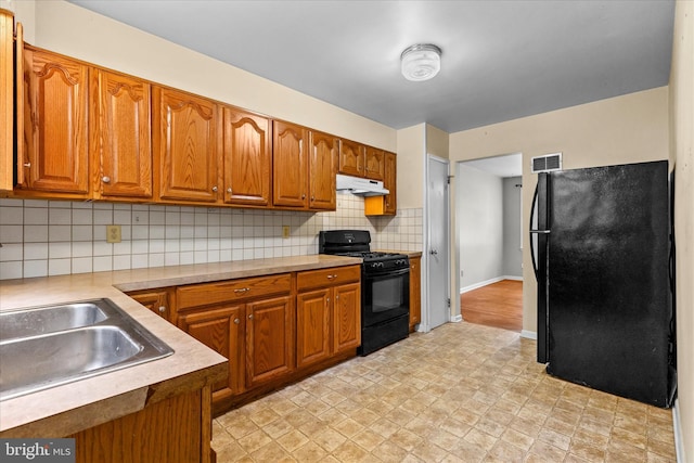 3415 E Market St, York, PA 17402 - kitchen featuring black appliances, under cabinet range hood, brown cabinetry, and light countertops