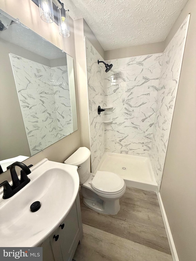4850 Magpie Ln, Waldorf, MD 20603 - bathroom with wood finished floors, a textured ceiling, toilet, vanity, and a walk in shower