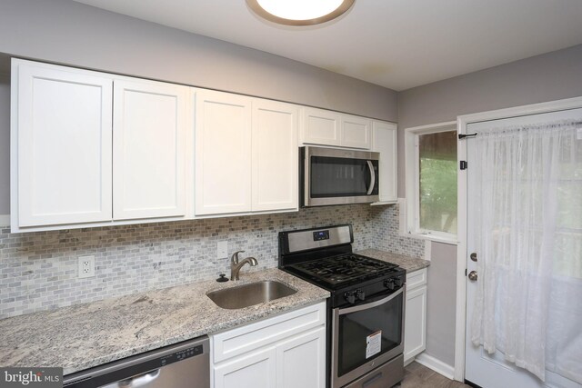 1932 Inverton Rd, Baltimore, MD 21222 - kitchen with appliances with stainless steel finishes, white cabinets, decorative backsplash, and light stone countertops