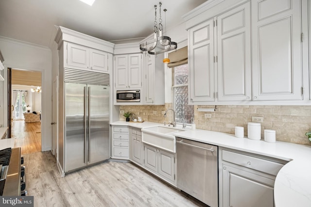 1827 Phelps Pl NW, Washington, DC 20008 - kitchen featuring built in appliances, a sink, crown molding, backsplash, and light wood-style floors