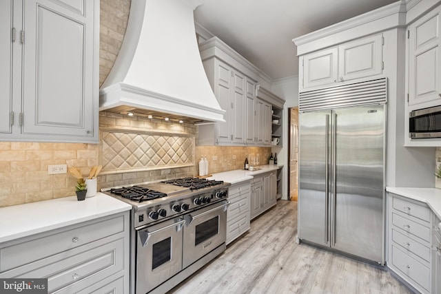 1827 Phelps Pl NW, Washington, DC 20008 - kitchen featuring premium appliances, custom exhaust hood, light wood finished floors, and light countertops