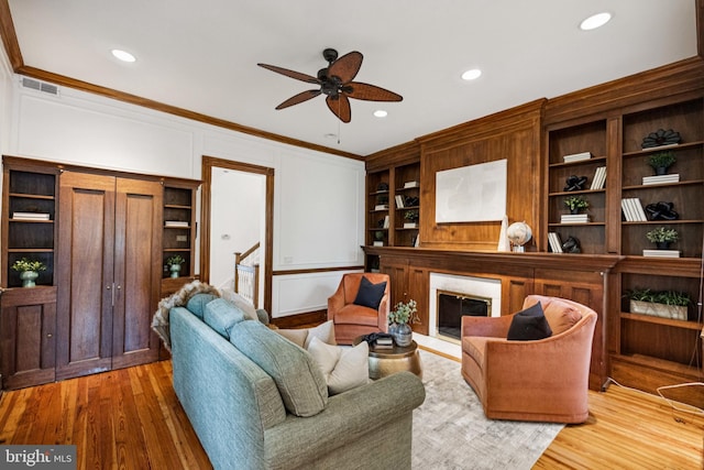 1827 Phelps Pl NW, Washington, DC 20008 - living area featuring crown molding, ceiling fan, built in shelves, wood finished floors, and a glass covered fireplace
