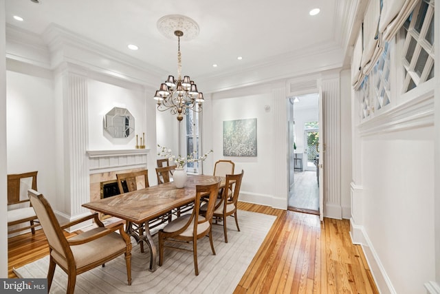 1827 Phelps Pl NW, Washington, DC 20008 - dining area with light wood finished floors, a fireplace, ornamental molding, a chandelier, and baseboards