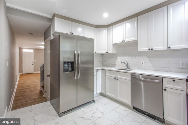 706 Cumberland St, Baltimore, MD 21217 - kitchen featuring appliances with stainless steel finishes, light marble finish flooring, a sink, light countertops, and white cabinets