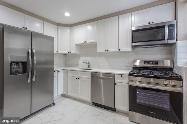 706 Cumberland St, Baltimore, MD 21217 - kitchen with stainless steel appliances, light countertops, white cabinetry, a sink, and light marble finish floors