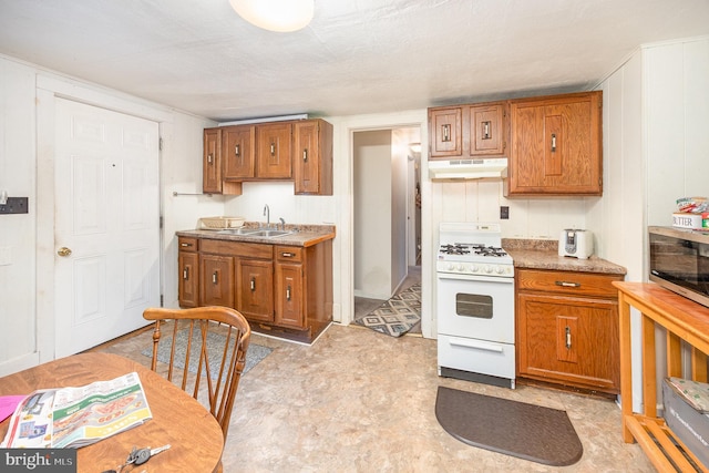 15-17 Locust St, Duncannon, PA 17020 - kitchen featuring white gas stove, under cabinet range hood, a sink, and brown cabinets