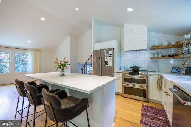 549 E Lafayette Dr, West Chester, PA 19382 - kitchen featuring stainless steel appliances, vaulted ceiling, a kitchen bar, open shelves, and wall chimney range hood