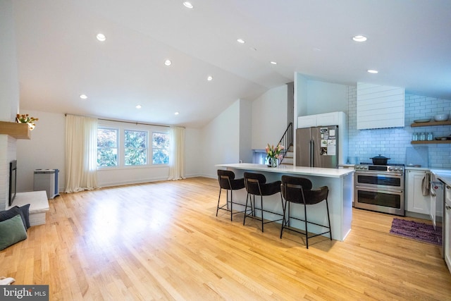 549 E Lafayette Dr, West Chester, PA 19382 - kitchen with appliances with stainless steel finishes, a breakfast bar area, lofted ceiling, a kitchen island, and light wood-style floors