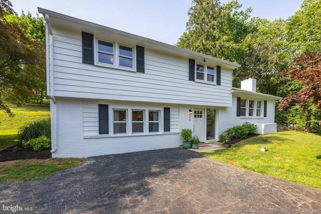 549 E Lafayette Dr, West Chester, PA 19382 - tri-level home featuring brick siding, a chimney, a front yard, entry steps, and a patio area