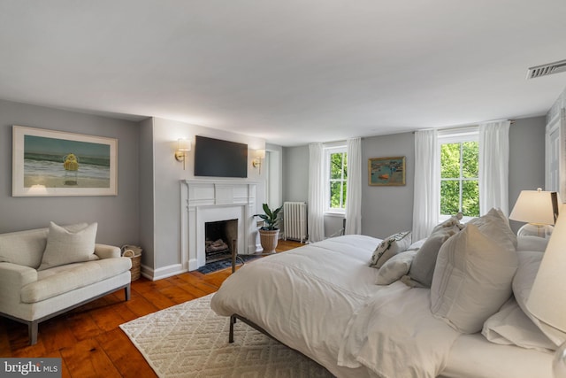 11 Conshohocken State Rd, Gladwyne, PA 19035 - bedroom with radiator heating unit, multiple windows, hardwood / wood-style flooring, and a fireplace with flush hearth
