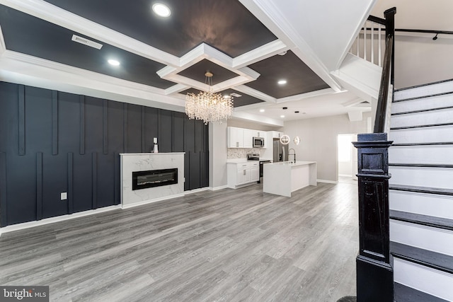 1607 Saint Stephens St, Baltimore, MD 21216 - unfurnished living room featuring coffered ceiling, stairs, a sink, a chandelier, and light wood-style flooring