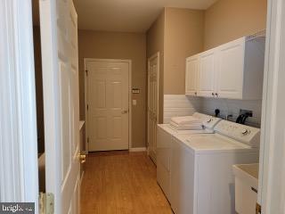 339 Carlisle Dr, Avondale, PA 19311 - laundry room featuring washing machine and dryer, cabinet space, and light wood-style floors