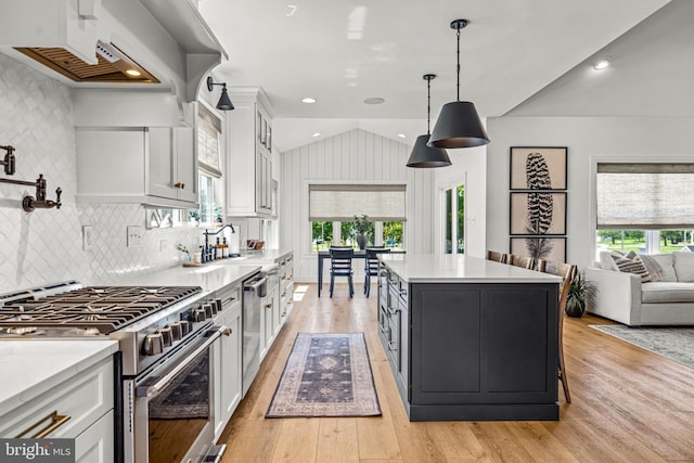 597 Zion Rd, Egg Harbor Township, NJ 08234 - kitchen featuring stainless steel appliances, white cabinets, vaulted ceiling, light countertops, and light wood-style flooring