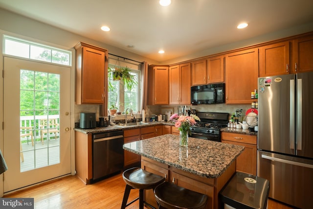 20468 Alicent Ter, Ashburn, VA 20147 - kitchen with black appliances, brown cabinets, dark stone counters, light wood-style flooring, and recessed lighting