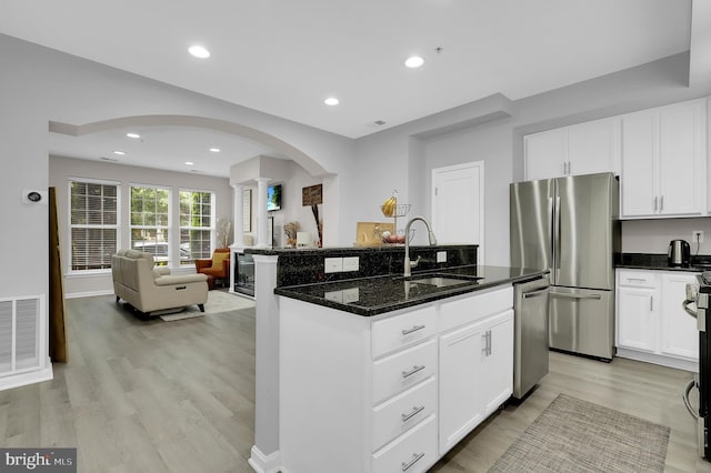 1813 Wheyfield Dr Unit 10-A, Frederick, MD 21701 - kitchen with stainless steel appliances, open floor plan, light wood-style flooring, arched walkways, and dark stone counters