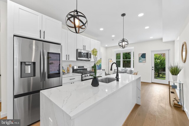 713 Tewkesbury Pl NW, Washington, DC 20012 - kitchen with appliances with stainless steel finishes, white cabinets, recessed lighting, a kitchen island with sink, and light wood-style flooring