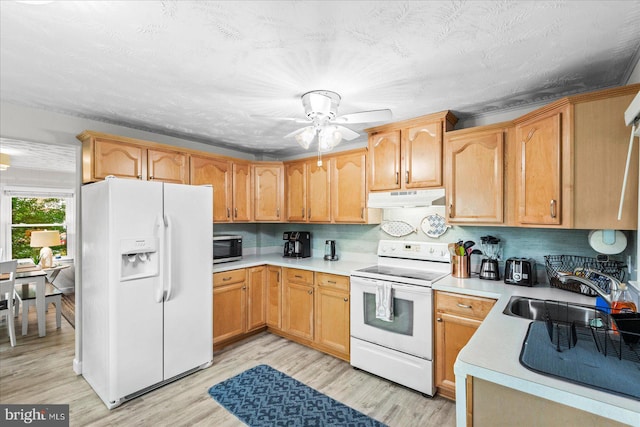 412 Marshall Ave, Colonial Beach, VA 22443 - kitchen featuring white appliances, under cabinet range hood, a sink, light countertops, and light wood finished floors