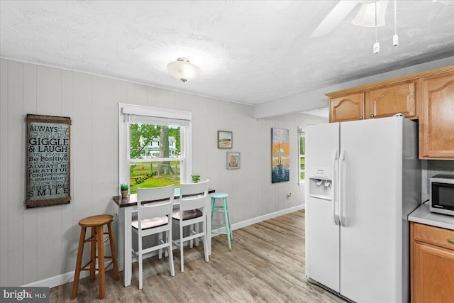 412 Marshall Ave, Colonial Beach, VA 22443 - kitchen featuring white refrigerator with ice dispenser, baseboards, light wood-type flooring, stainless steel microwave, and a textured ceiling
