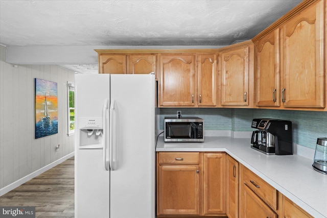 412 Marshall Ave, Colonial Beach, VA 22443 - kitchen with white refrigerator with ice dispenser, stainless steel microwave, wood finished floors, light countertops, and baseboards