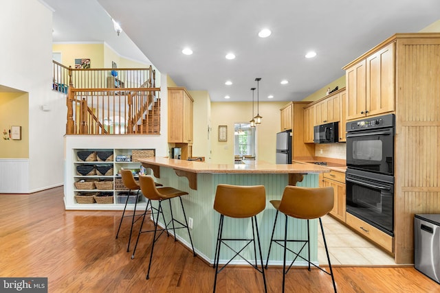 240 Charleston Rd, Ocean Pines, MD 21811 - kitchen featuring light brown cabinetry, black appliances, a kitchen breakfast bar, light wood-type flooring, and recessed lighting