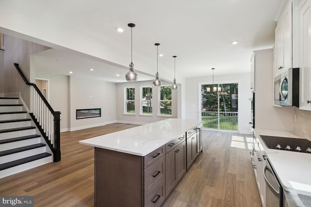 4010 Milner Rd, Nottingham, MD 21236 - kitchen featuring stainless steel appliances, wood finished floors, a kitchen island, white cabinetry, and dark brown cabinetry