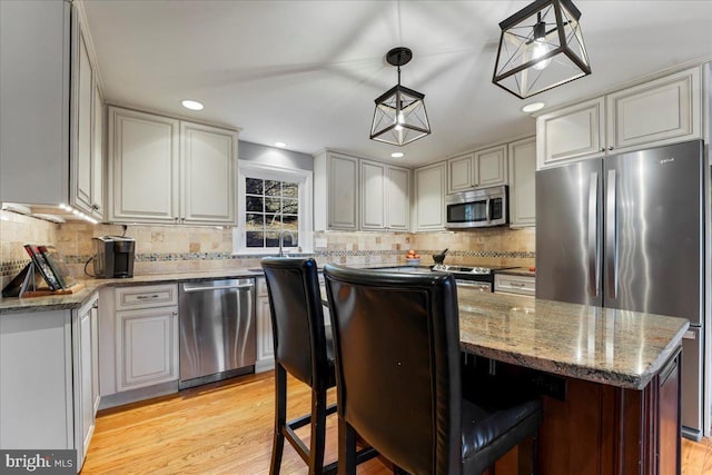 601 Crum Creek Rd, Media, PA 19063 - kitchen with appliances with stainless steel finishes, tasteful backsplash, a kitchen island, light stone counters, and light wood-style flooring