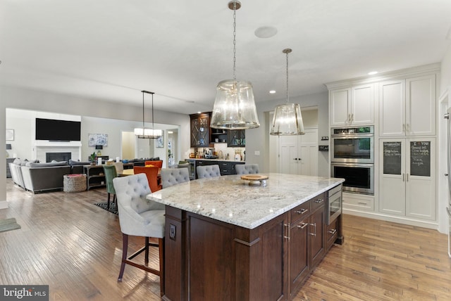 415 Pyles Mountain Ln, Avondale, PA 19311 - kitchen featuring double oven, hardwood / wood-style floors, a kitchen bar, dark brown cabinets, and decorative light fixtures