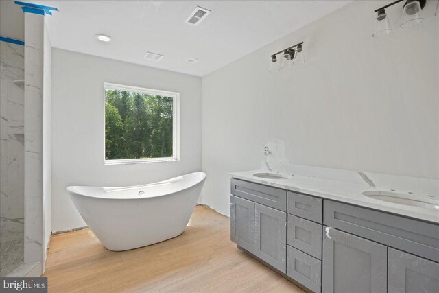 7016 Grace Landing Ct, Hughesville, MD 20637 - bathroom featuring a freestanding bath, double vanity, wood finished floors, a marble finish shower, and recessed lighting