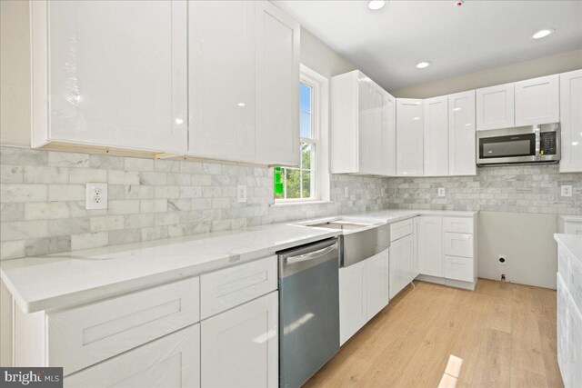 7016 Grace Landing Ct, Hughesville, MD 20637 - kitchen featuring stainless steel appliances, light stone countertops, white cabinetry, light wood finished floors, and backsplash