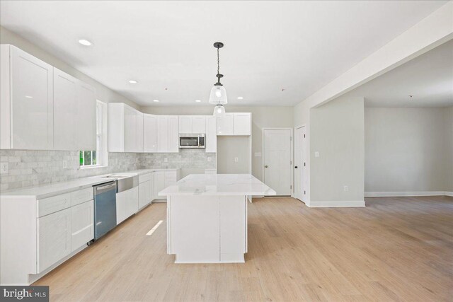 7016 Grace Landing Ct, Hughesville, MD 20637 - kitchen with appliances with stainless steel finishes, backsplash, a center island, white cabinets, and light wood-style floors