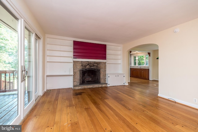 1901 Acorn Ln, Abington, PA 19001 - unfurnished living room with arched walkways, hardwood / wood-style flooring, a stone fireplace, and built in features