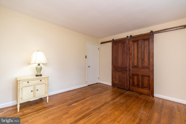 1901 Acorn Ln, Abington, PA 19001 - unfurnished bedroom featuring wood-type flooring, a barn door, and baseboards