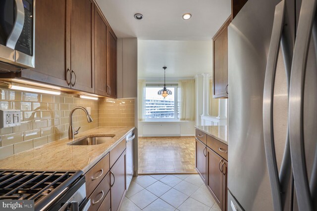 2475 Virginia Ave NW Unit 930, Washington, DC 20037 - kitchen featuring appliances with stainless steel finishes, backsplash, light stone counters, brown cabinets, and light tile patterned flooring
