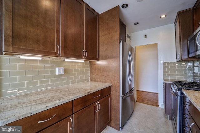 2475 Virginia Ave NW Unit 930, Washington, DC 20037 - kitchen with stainless steel appliances, light stone counters, decorative backsplash, and light tile patterned floors