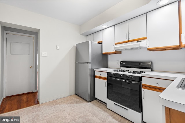 1238 Durfor St, Philadelphia, PA 19148 - kitchen with under cabinet range hood, gas range, light countertops, white cabinetry, and freestanding refrigerator