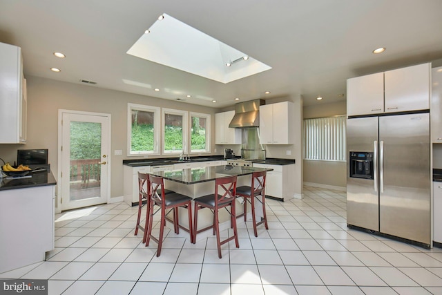 3820 Lorcom Ln, Arlington, VA 22207 - kitchen with stainless steel fridge, wall chimney exhaust hood, dark countertops, a skylight, and recessed lighting