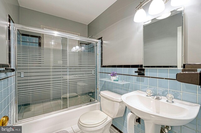 3820 Lorcom Ln, Arlington, VA 22207 - bathroom featuring toilet, tile walls, combined bath / shower with glass door, and a sink