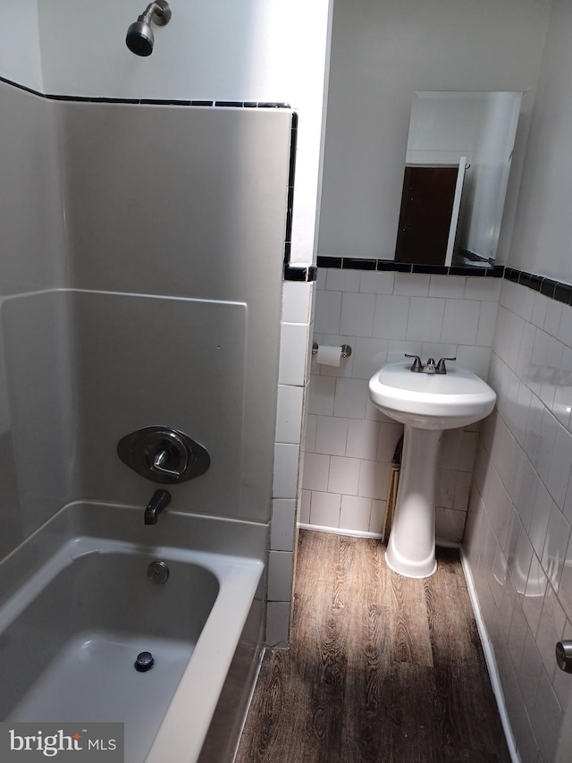 513 N Highland Ave, Baltimore, MD 21205 - full bath with tile walls, wood finished floors, shower / tub combination, and a wainscoted wall