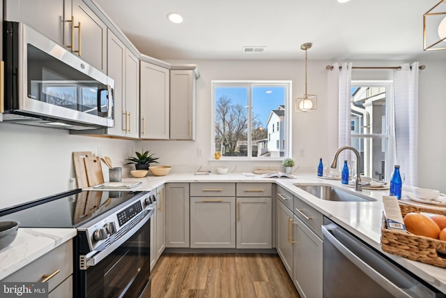 1807 Arch St Unit 21E, Norristown, PA 19401 - kitchen featuring appliances with stainless steel finishes, gray cabinetry, a sink, light wood-style flooring, and light stone counters