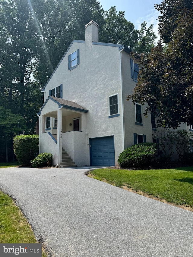 1708 Stoneham Dr Unit 1708, West Chester, PA 19382 - view of front facade featuring stucco siding, a garage, a chimney, and driveway