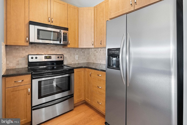 1100 S Broad St Unit 404C & # 212P, Philadelphia, PA 19146 - kitchen with appliances with stainless steel finishes, light wood-style flooring, tasteful backsplash, and dark stone counters